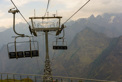 Overhead cable car over mountains against sky