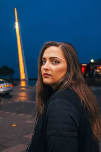 Side view portrait of young woman standing against clear sky