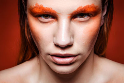 Close-up portrait of serious young woman with orange eyebrows