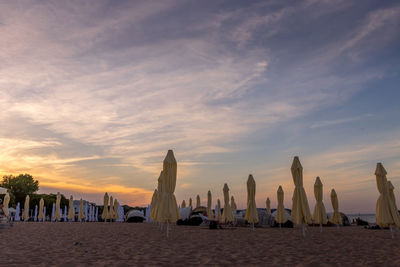 Panoramic view of people at beach against sky during sunset