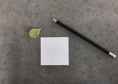 High angle view of paper and pencil on cement