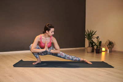 Young woman doing yoga on yoga mat in atmospheric yoga studio