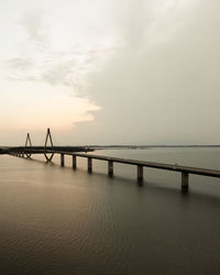 Bridge over sea against sky during sunset