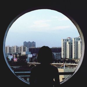 Rear view of silhouette man looking through window