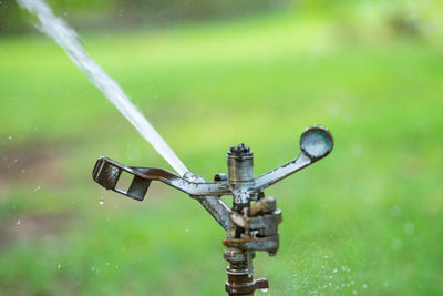 Water sprinkler spraying water on grass field in park