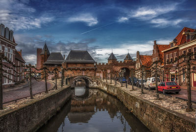 Bridge over canal amidst buildings in city against sky