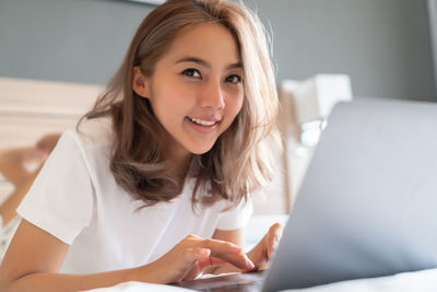 Portrait of smiling young woman using laptop