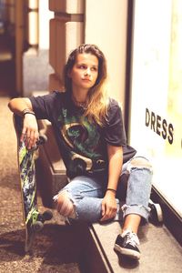 Portrait of a young woman sitting on window