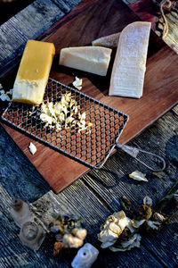 Blocks of smoked cheese and parmesan with vintage metal cheese grater on wood cutting board