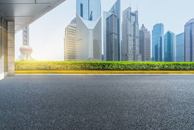 City street by modern buildings against sky