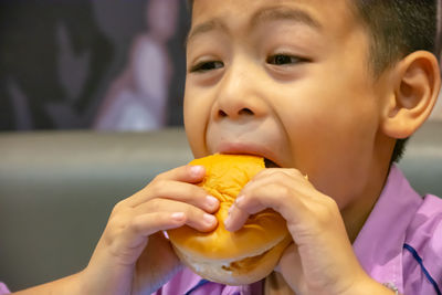 Close-up of boy looking away while eating burger