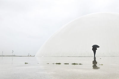 Side view of man standing in sea during rainy season