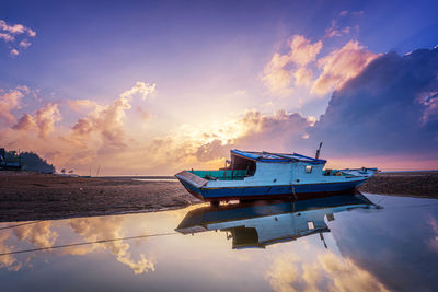 Boats moored in sea against sky during sunrise