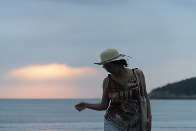 Man standing by sea against sky during sunset