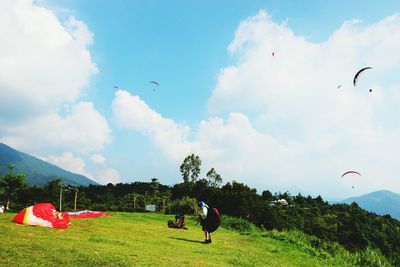People paragliding over field
