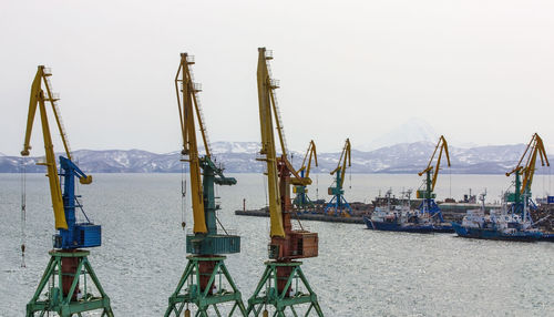 View on trading seaport with cranes, cargoes and the ship in front of snowy mountains