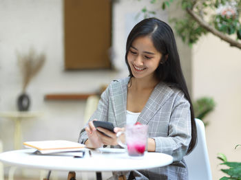 Young woman using phone on table