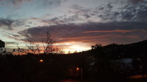 Silhouette trees against dramatic sky during sunset