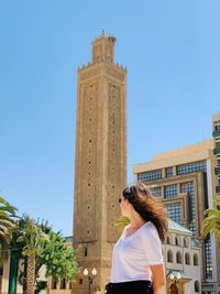 Woman standing in city against clear sky