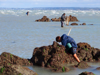 People fishing in sea against sky