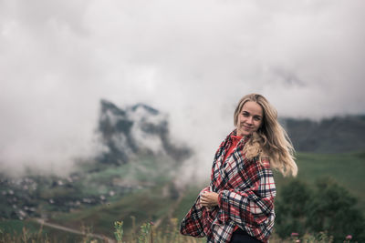 Portrait of smiling young woman standing against landscape 