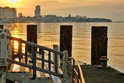 Buildings by sea against sky during sunset