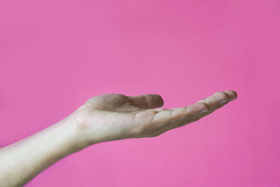 Close-up of woman hand against pink background