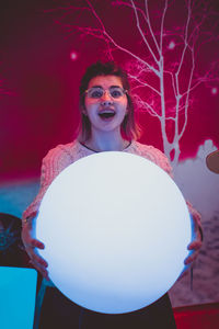 Portrait of woman standing against illuminated wall