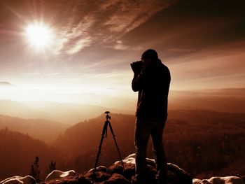 Photographer takes picture of freeze autumnal daybreak, rocks covered with fresh powder snow. 