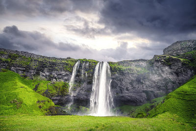 Scenic view of waterfall against sky