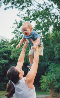 Mother and son on tree against plants