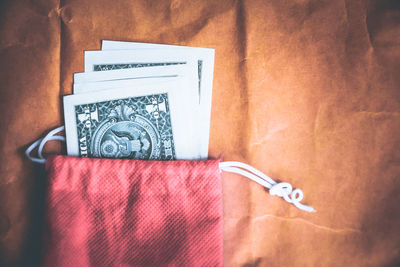 High angle view of currencies with purse on brown paper