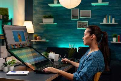 Young woman using mobile phone while sitting on table