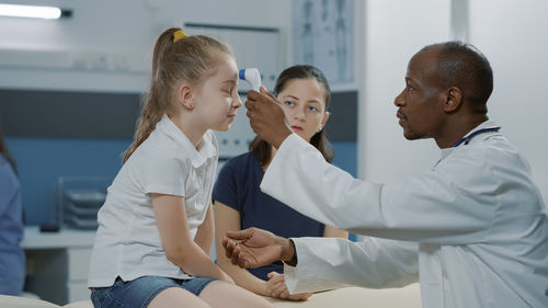 Doctor checking girls temperature
