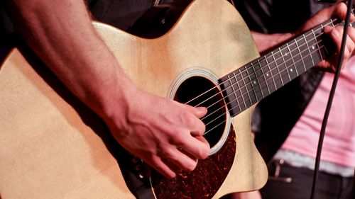 Midsection of man playing guitar