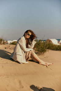 Young woman sitting on sand at desert