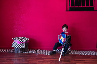 Full length portrait of young man sitting on table