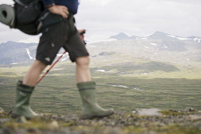 Low section of hiker walking against mountains