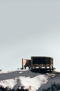 Abandoned building on field against clear sky during winter