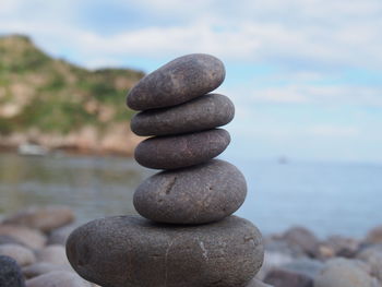 Stack of stones in sea against sky