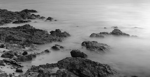 Scenic view of rocks in sea against sky