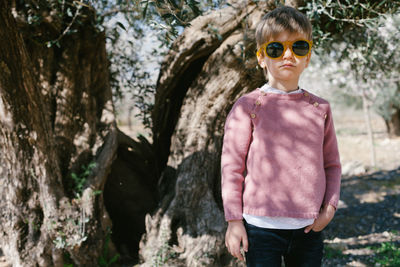 Portrait of boy wearing sunglasses standing against tree