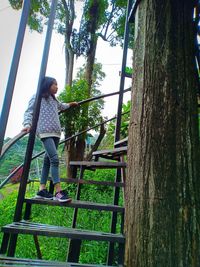 Girl standing by tree trunk