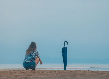 Rear view of woman on beach against clear sky