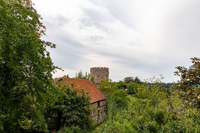 Old building by trees against sky