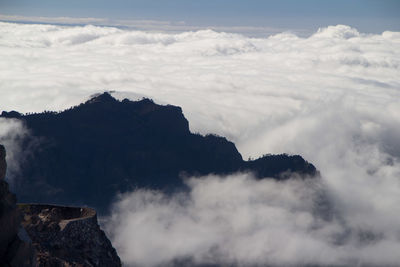 Scenic view of mountain over cloudscape 