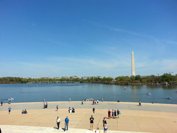 People on shore against blue sky