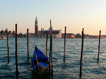 Gondolas moored on grand canal against sky during sunset