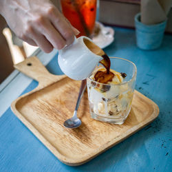 Cropped hand pouring chocolate sauce on ice cream