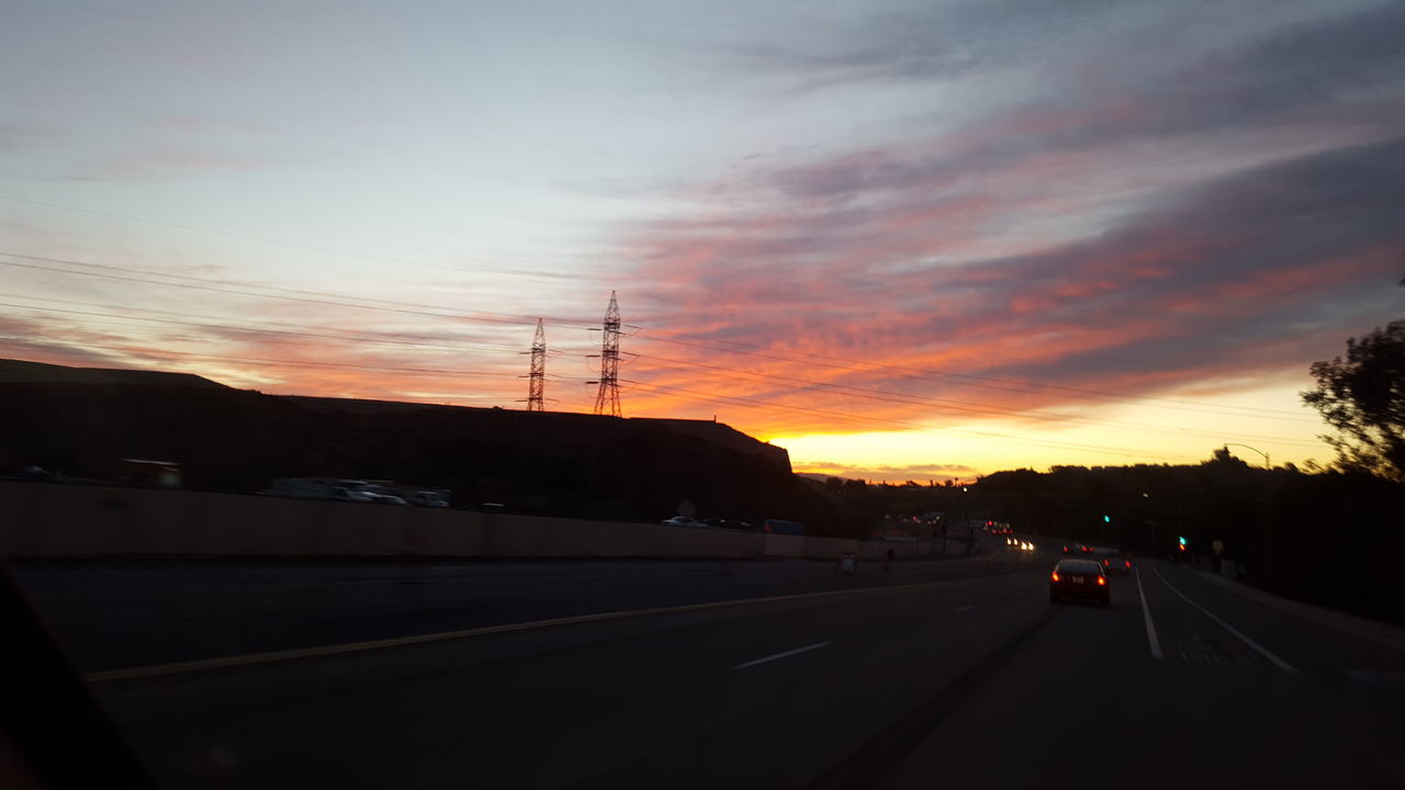 sunset, road, transportation, sky, silhouette, electricity pylon, the way forward, power line, cloud - sky, car, street, tree, orange color, beauty in nature, scenics, nature, land vehicle, road marking, cloud, tranquil scene